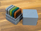 Open gray memory card case holding colored memory cards next to its lid