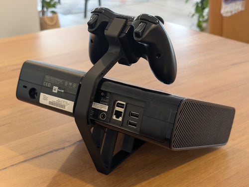 Xbox 360 console tilted on a 3D printed stand, rear view, with controller mount